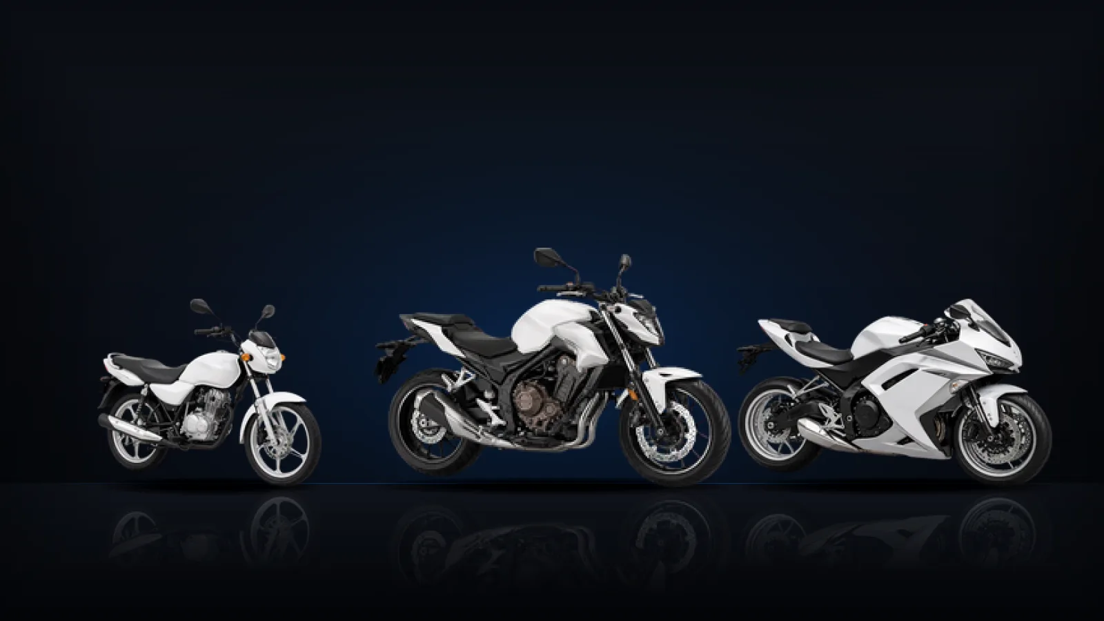 A commuter motorcycle, a naked roadster and a sport bike lined up on a dark studio floor