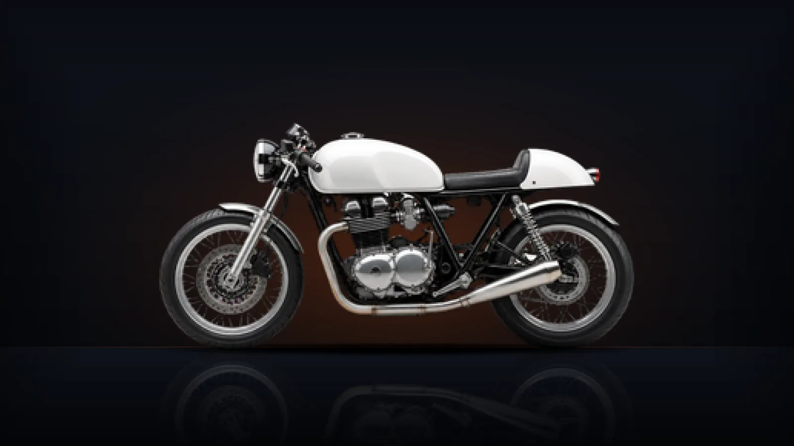 A white café-racer motorcycle showing its engine, lit warmly from behind