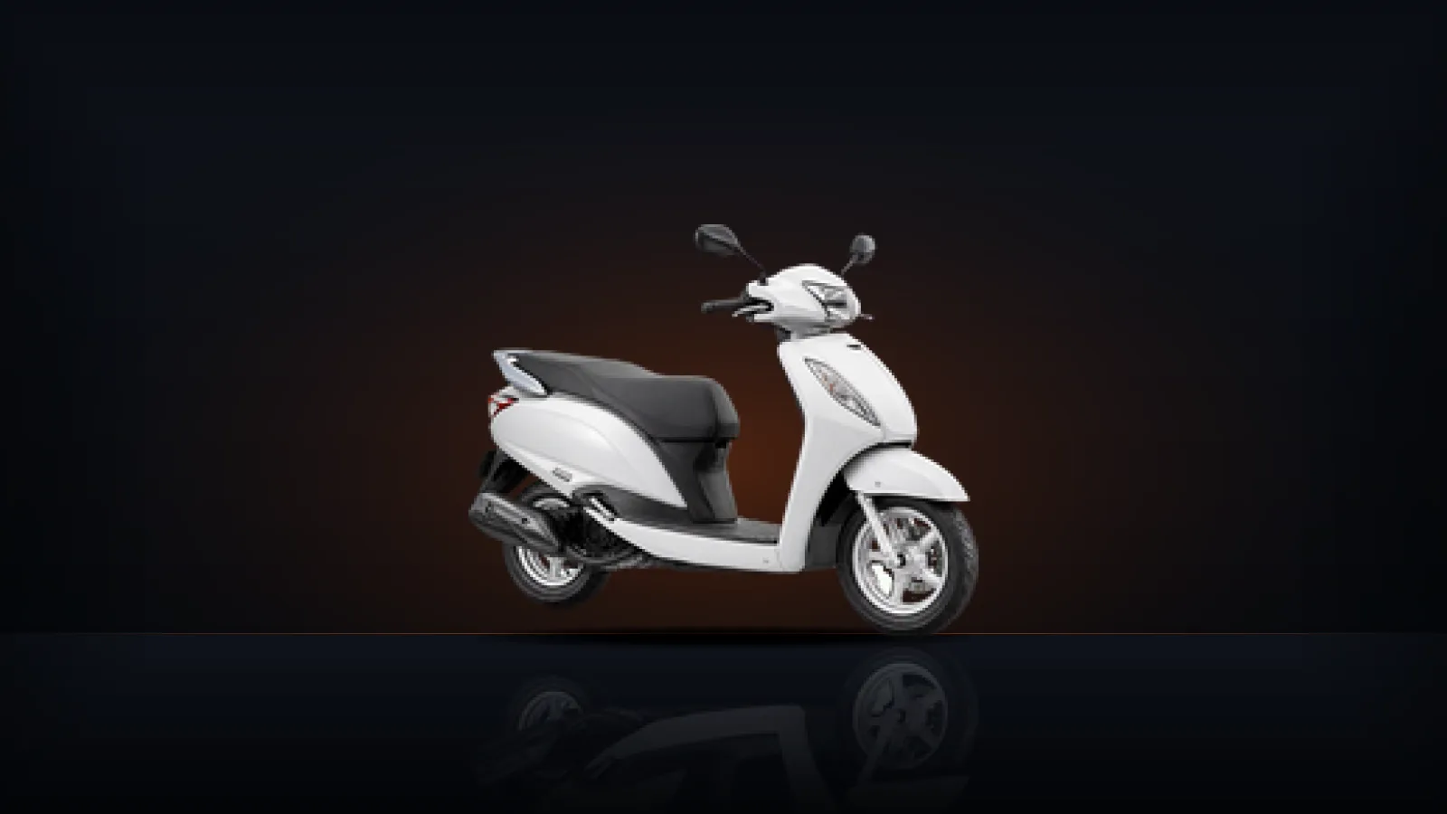 A white automatic scooter on a dark floor with a warm orange light behind it