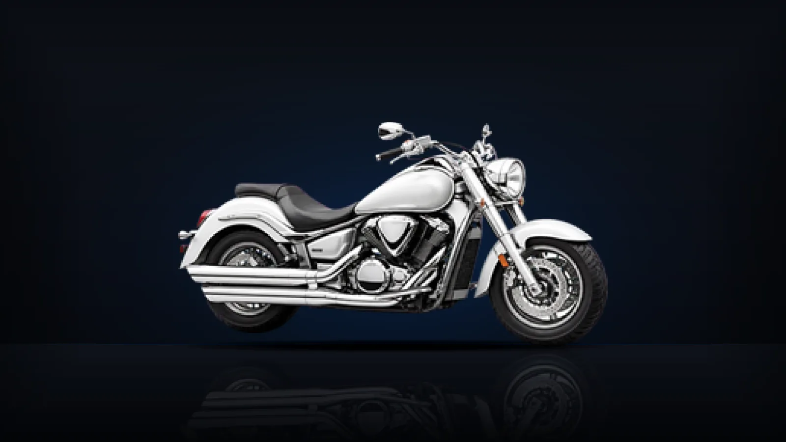 A chrome and white cruiser motorcycle on a dark floor