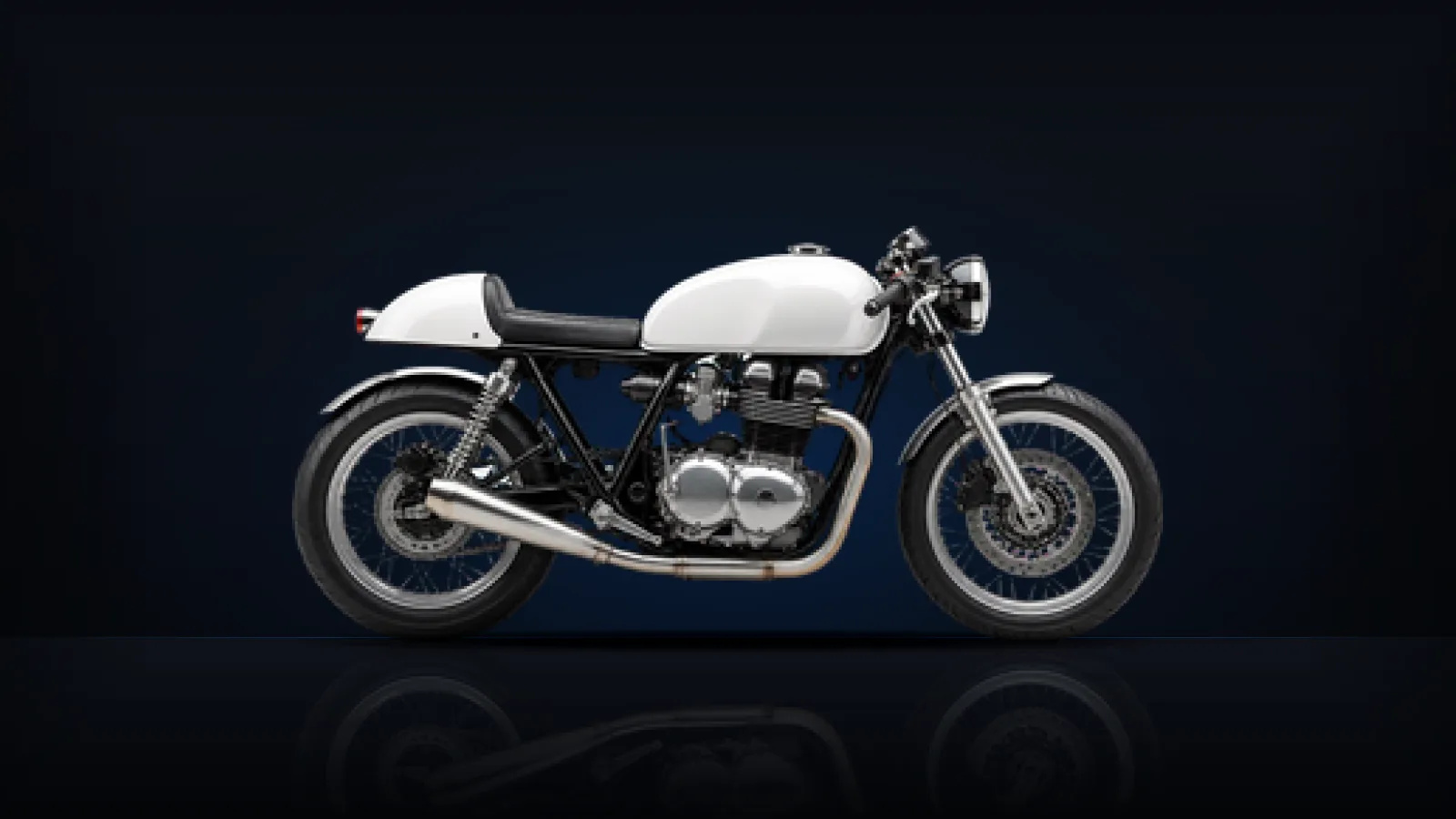 A white café-racer style motorcycle on a dark studio floor